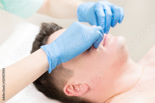 Cosmetic procedure for applying a therapeutic mask to a young man in a beauty salon.