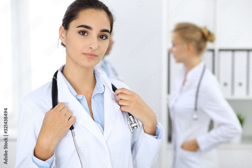 Doctor woman in clinic with colleagues at the background. Hispanic or latin american staff in medicine Doctor woman in clinic with colleagues at the background. Hispanic or latin american staff in medicine