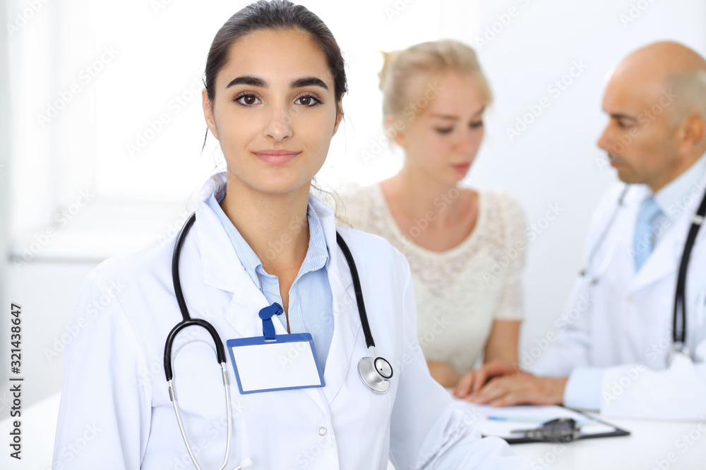 Doctor woman in clinic with colleagues at the background. Hispanic or latin american staff in medicine Doctor woman in clinic with colleagues at the background. Hispanic or latin american staff in medicine