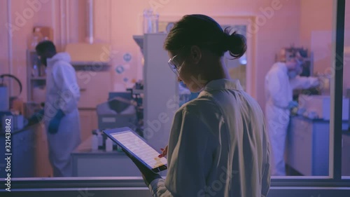 Female senior scientist with laptop managing medical project supervising her team.