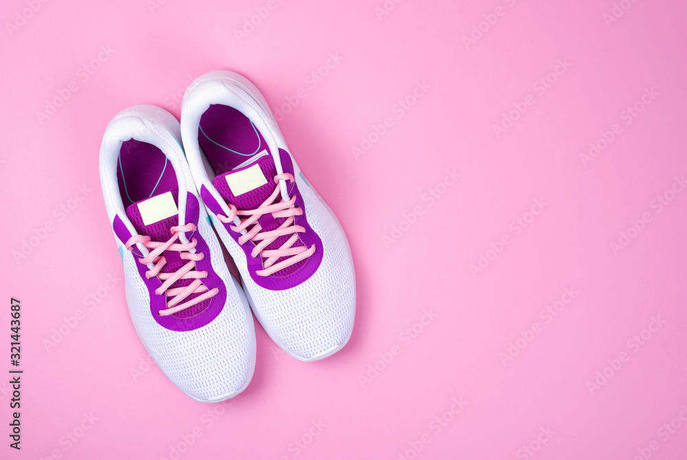 Women's white sneakers on a pink background. Women's white sneakers on a pink background.