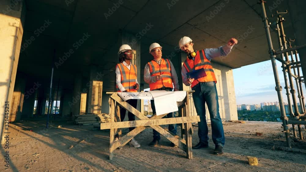Professional builders discuss construction works on a site. Professional builders discuss construction works on a site.