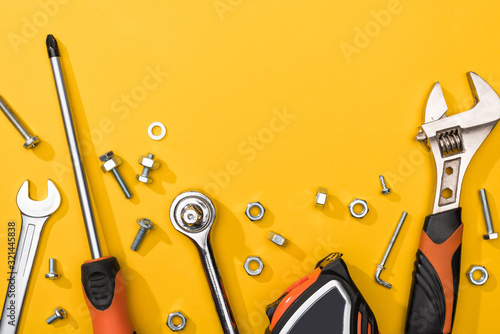 Top view of tool set with nuts and bolts on yellow background