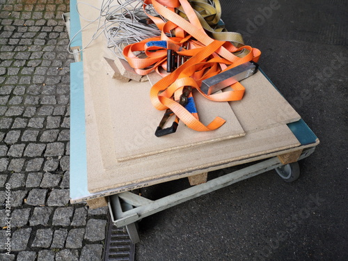 Plattformwagen mit Rollen und Spanplatten auf Kopfsteinpflaster mit Spanngurten in Orange für den Umzug durch ein Umzugsunternehmen in der City und Innenstadt von Frankfurt am Main in Hessen photo