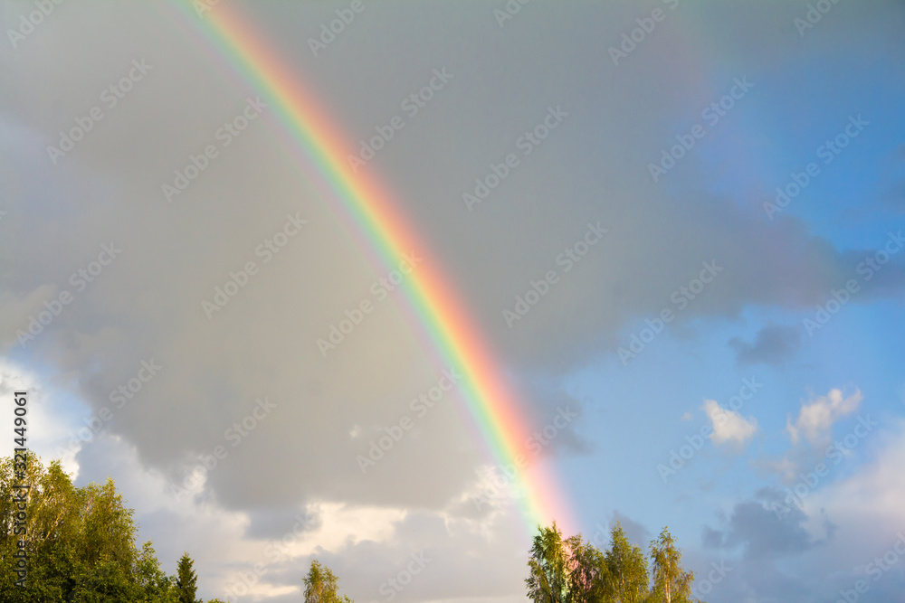 Rainbow against a background of blue sky and dark clouds Rainbow against a background of blue sky and dark clouds