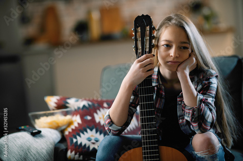 Cute little girl playing guitar. Teenage girl learning to play guitar
