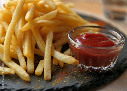 Tasty French fries with red sauce served on table in cafe, closeup