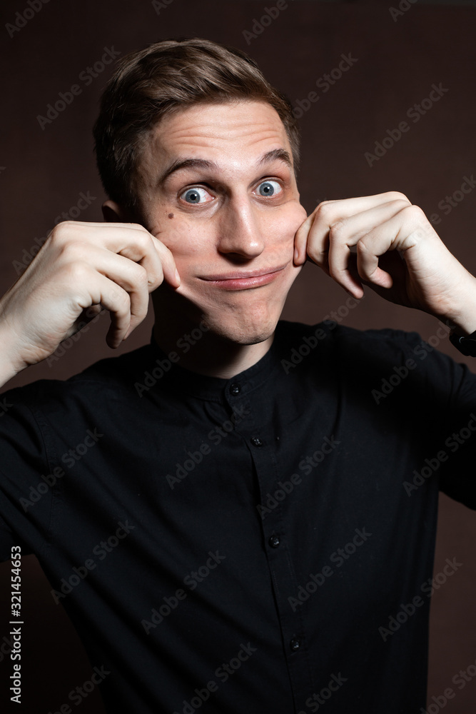 A man in round glasses and a black shirt is grimacing A man in round glasses and a black shirt is grimacing