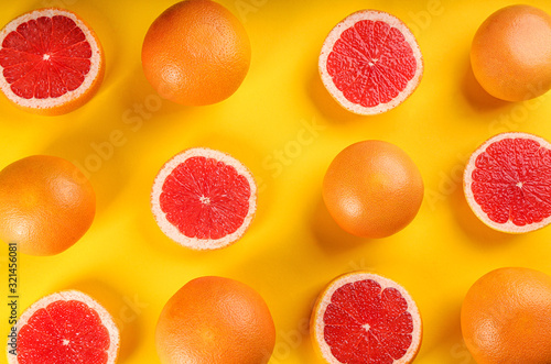 Cut and whole ripe grapefruits on yellow background  flat lay