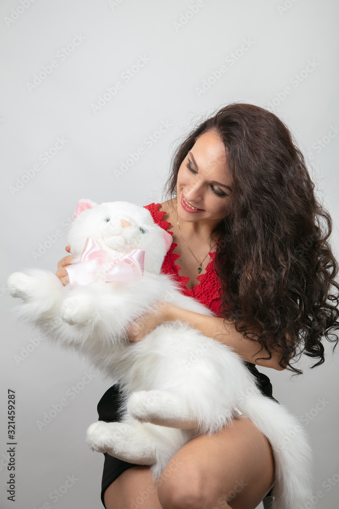 Beautiful brunette with a big, white, toy cat. Congratulation concept Beautiful brunette with a big, white, toy cat. Congratulation concept