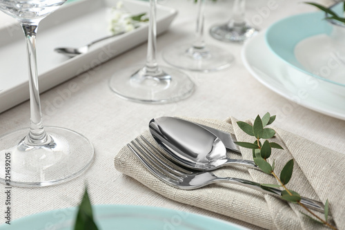 Elegant cutlery with green leaves on table. Festive setting