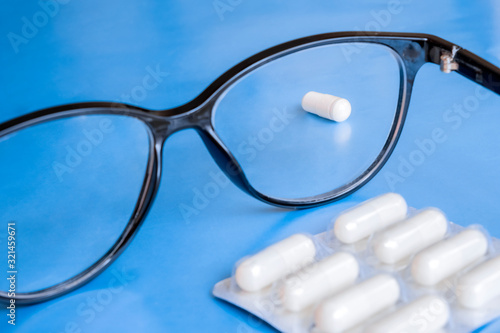 Glasses with white pills  eye care concept. Health care. Ophthalmology concept. Eyesight concept.