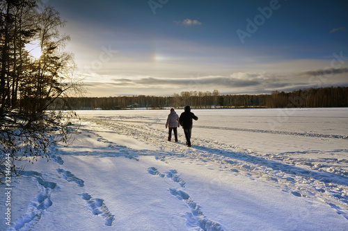 Winter landscape at sunset by a snowy forest lake. Winter forest.
