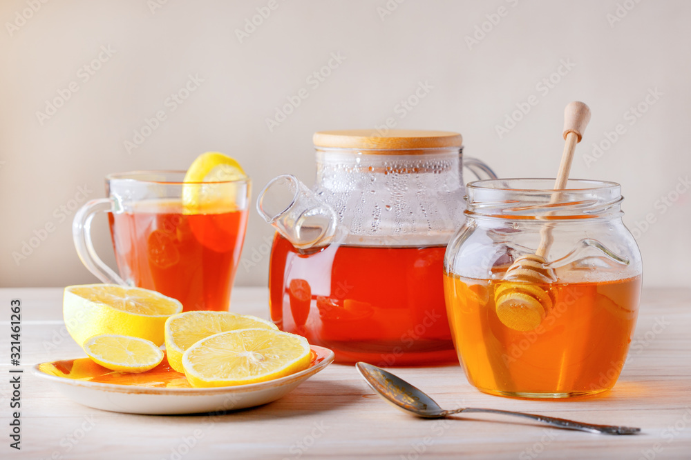 Fresh brewed black tea in a glass teapot and honey in bowl. Fresh brewed black tea in a glass teapot and honey in bowl.