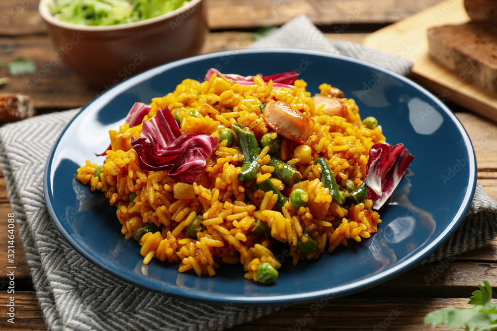 Delicious rice pilaf with chicken and vegetables on wooden table Delicious rice pilaf with chicken and vegetables on wooden table