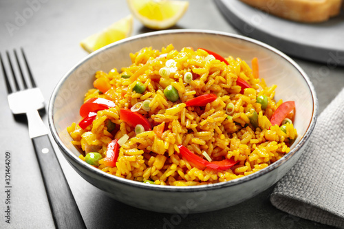 Delicious rice pilaf with vegetables on grey table