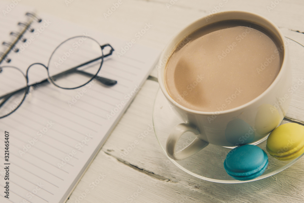 A cup of coffee with milk, glasses and notebook A cup of coffee with milk, glasses and notebook