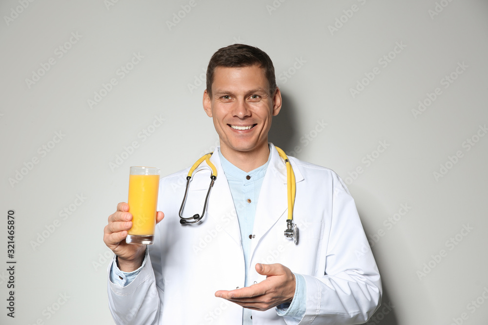 Nutritionist with glass of juice on light grey background Nutritionist with glass of juice on light grey background