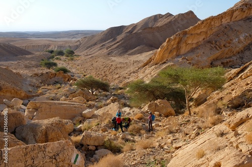 Unrecognized group of hikers taking rest on tourist trail in Small Crater, Negev desert.