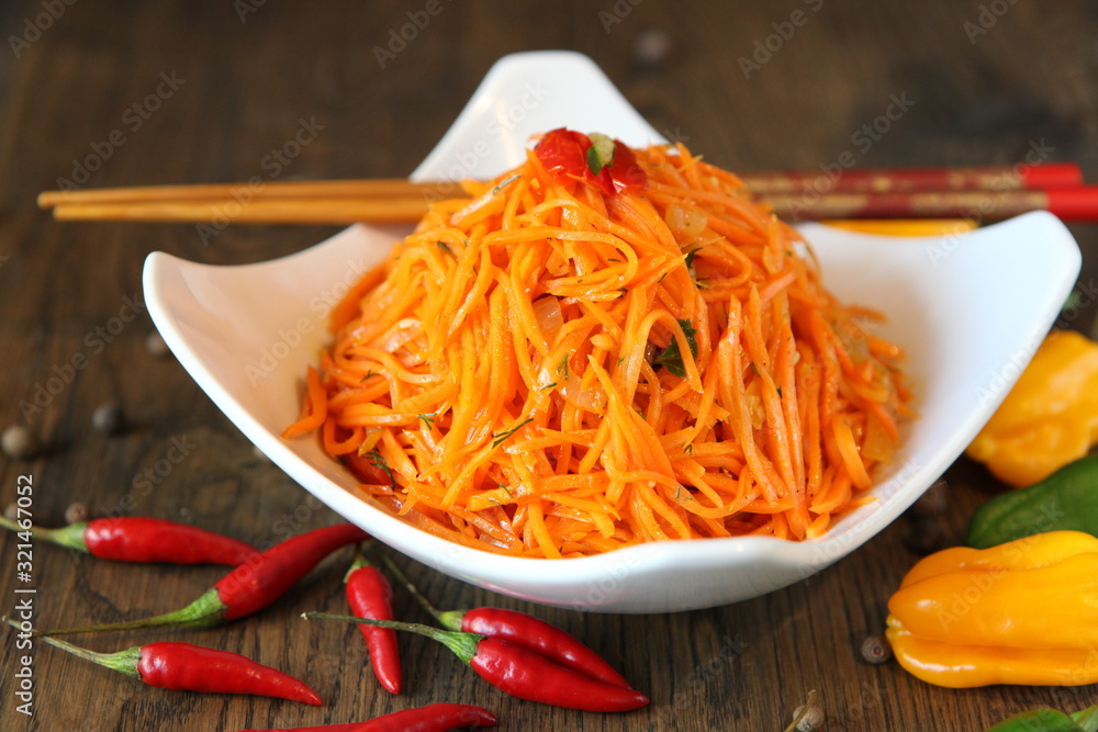 Carrot Korean meat salad with chopsticks on wooden oak table Carrot Korean meat salad with chopsticks on wooden oak table