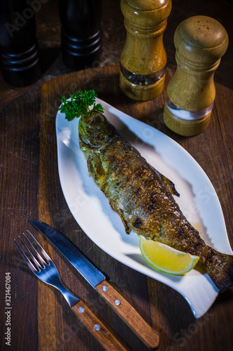 Baked mackerel with lemon and parsley on a white plate
