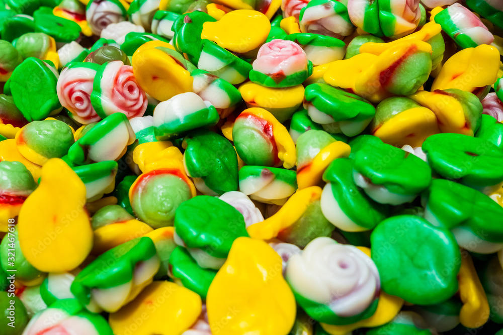 Bright green, yellow, berry and pink slices of marmalade chewing sweets in the form of rosebuds. Sweet beautiful delicacy made from gel fruit juices. Colorful background. Randomly heaped goodies. Bright green, yellow, berry and pink slices of marmalade chewing sweets in the form of rosebuds. Sweet beautiful delicacy made from gel fruit juices. Colorful background. Randomly heaped goodies.
