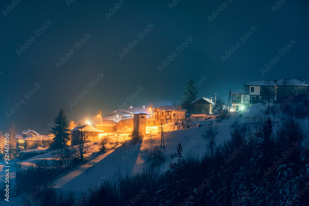 Fototapeta premium Small village in the snowy mountains in winter night