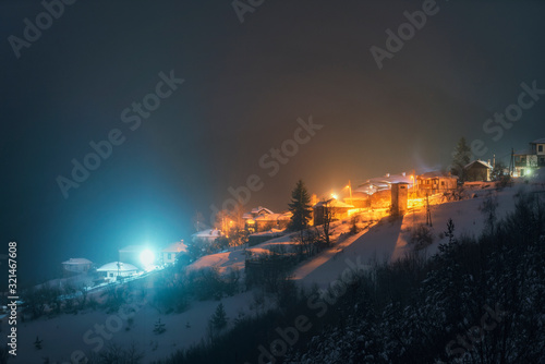 Night landscape. Winter in Rhodope mountain, Bulgaria, Vrata village. Light in windows of wooden houses. 