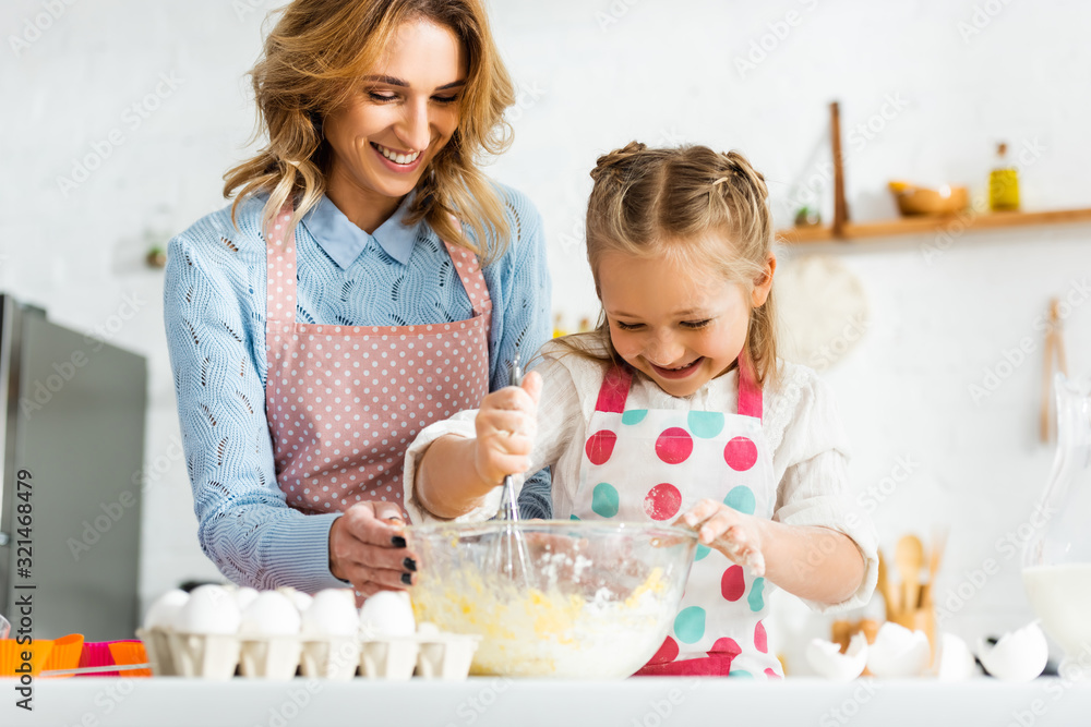 Beautiful attractive mother and cute daughter happy and positive cooking cupcakes together at home Beautiful attractive mother and cute daughter happy and positive cooking cupcakes together at home