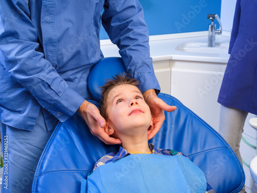 Dental visit to a child with an open mouth sitting in an inclined chair