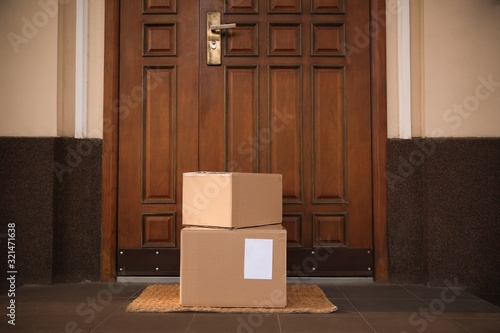 Fotografie Delivered parcels on door mat near entrance