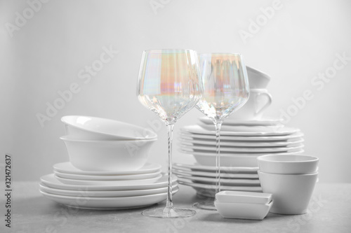Set of clean dishes and glasses on light grey table