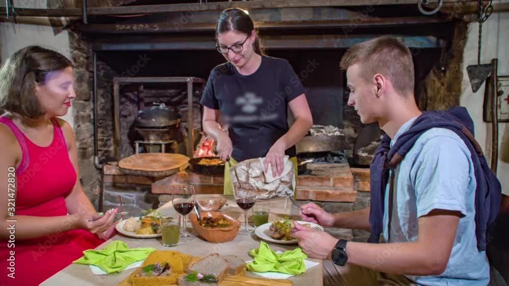 Slow motion shot of waitress slicing a homemade loaf of bread in front of a couple having dinner Slow motion shot of waitress slicing a homemade loaf of bread in front of a couple having dinner