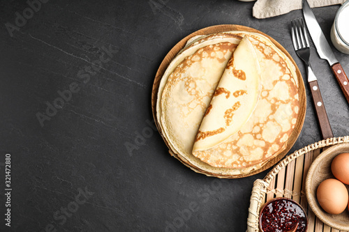 Flat lay composition with fresh thin pancakes on black table. Space for text