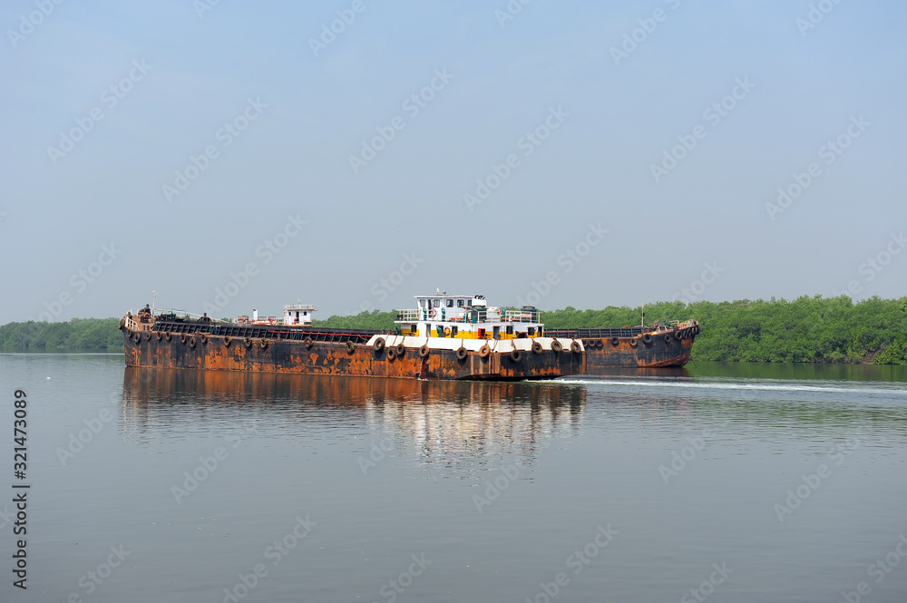 Natural landscape. Water transport. Barge floating on the river. Cargo ship, Mandovi River in Goa, India.
