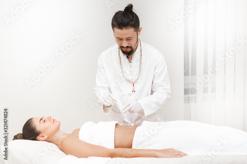 Oriental medicine doctor doing acupuncture stomachs to relieve a woman's stomach pain. Woman enjoys acupuncture