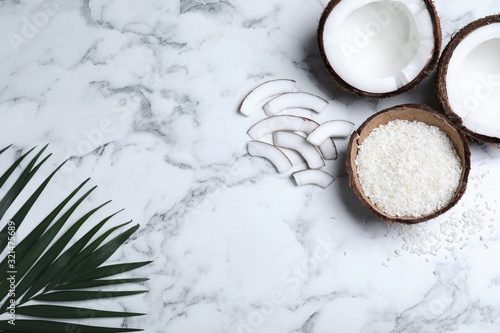 Flat lay composition with fresh coconut flakes on white marble table. Space for text