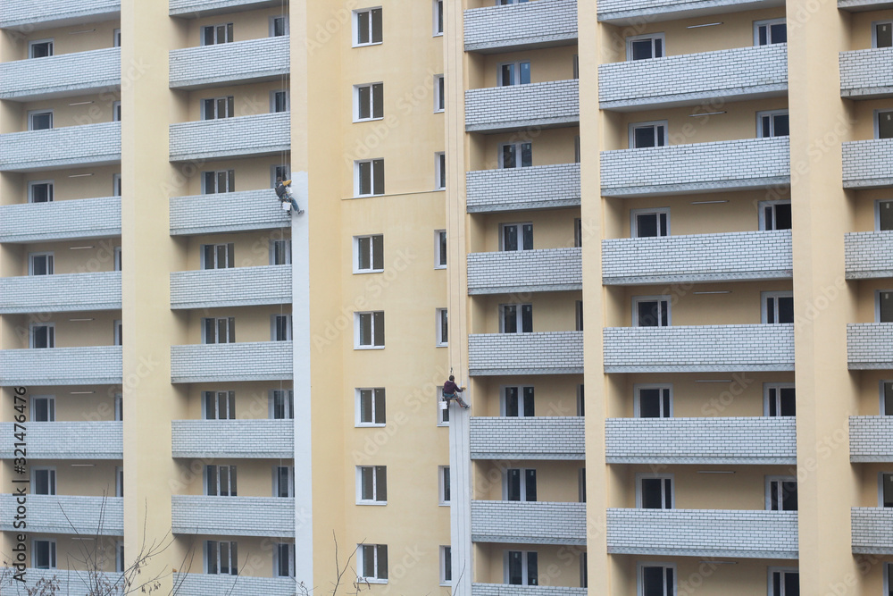 Two male workers are painting the outside of the tall building, By tying yourself to the rope, to job concept.