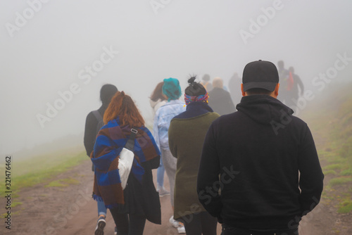 Fototapeta Back view of refugees walk to the border in a cold day under fog