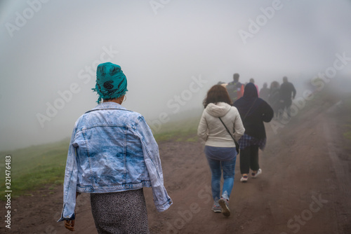 Papier peint Back view of refugees walk to the border in a cold day under fog