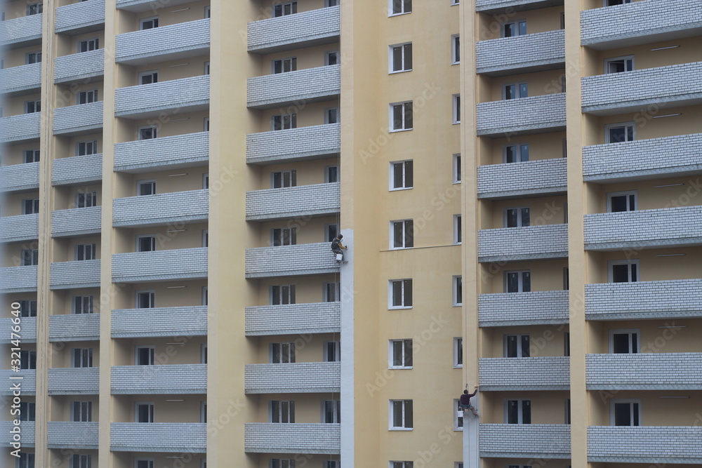 Two male workers are painting the outside of the tall building, By tying yourself to the rope, to job concept. Two male workers are painting the outside of the tall building, By tying yourself to the rope, to job concept.