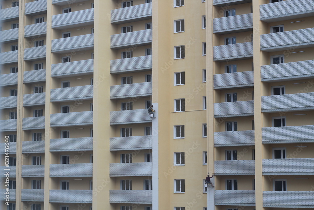 Two male workers are painting the outside of the tall building, By tying yourself to the rope, to job concept.