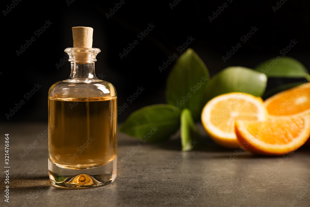 Bottle of essential oil and citrus fruits on grey table. Space for text Bottle of essential oil and citrus fruits on grey table. Space for text