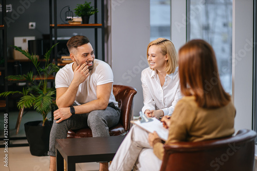 smiling caucasian couple sit in own office of family psychologist, happy sit having conversation with therapist, they want to solve problems with emotional side of relationship. people, family concept © Roman