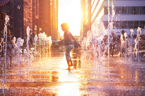 Tela Child run and play on street fountain on Philadelphia square over sunset near ci