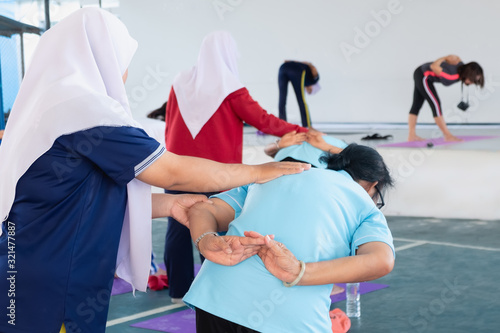 Posture of exercise with yoga There are participants of all ages, both young and old. With a Muslim female trainer closely