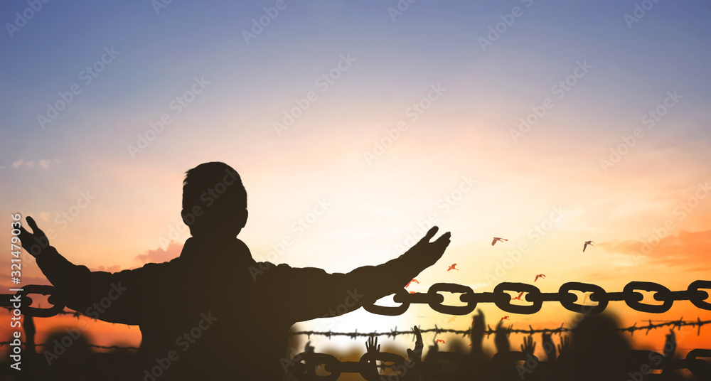 ChinaClosed concept: Silhouette refugee hands raising and barbed wire on sunset sky background