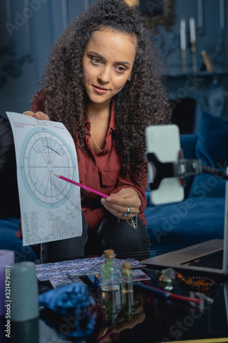 Foto Attractive female astrologer demonstrating a natal chart