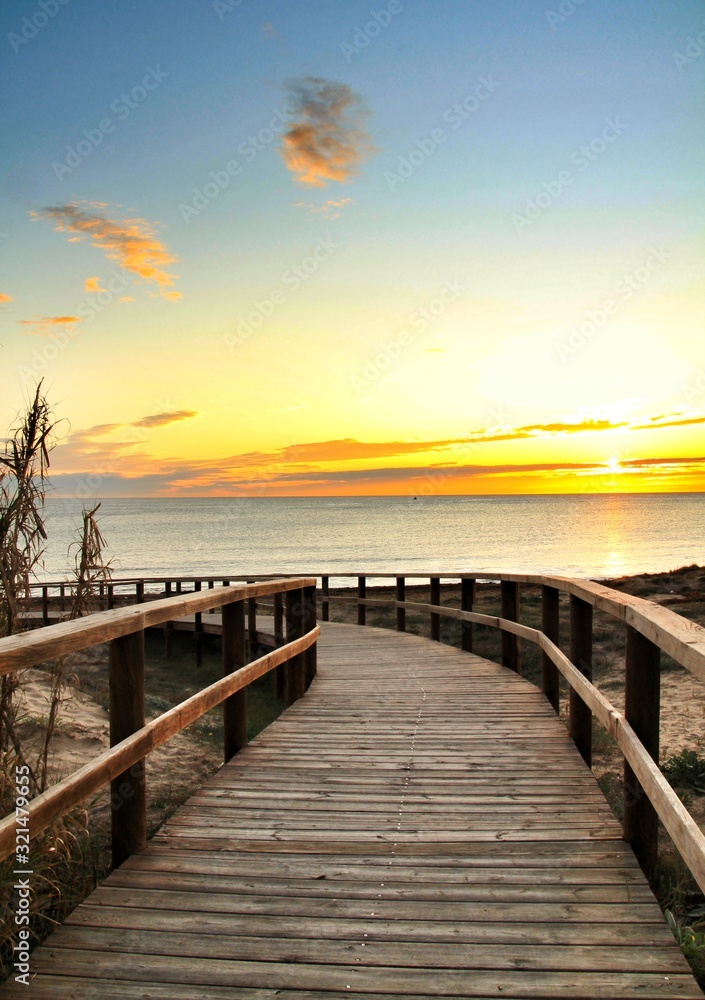 Fototapeta premium Wooden walkway to the beach at sunrise in Alicante, Spain
