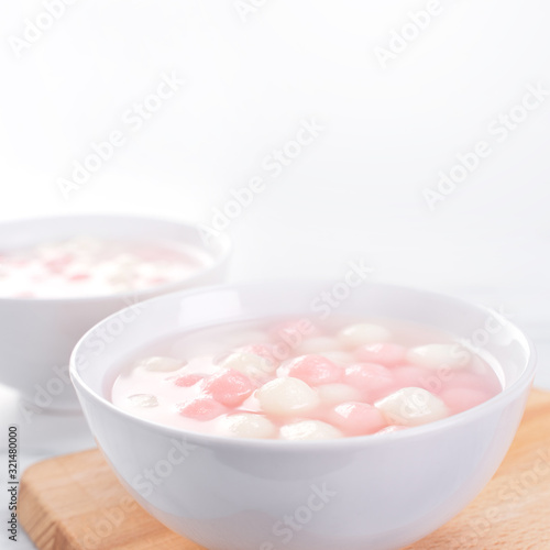 Tang yuan, tangyuan, delicious red and white rice dumpling balls in a small bowl. Asian traditional festive food for Chinese Winter Solstice Festival, close up.